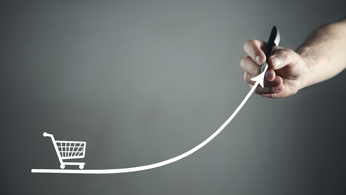 A person’s hand is drawing a graphic of a shopping cart driving on an upward curving line representing the straightforward process of starting to sell on multiple marketplaces.