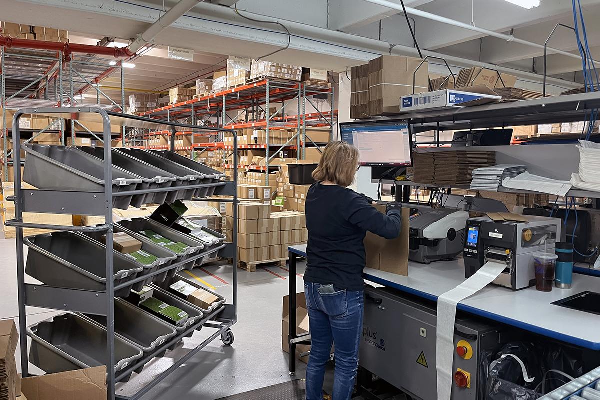 Warehouse worker at packing station with trolley